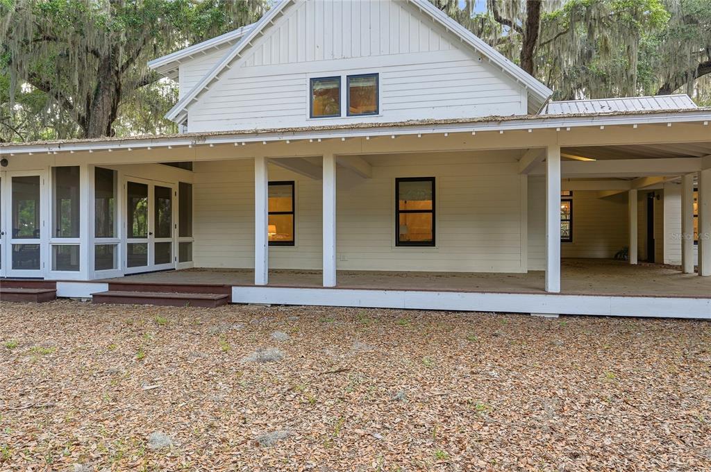 A white house features a large covered porch, a screened-in area, and a carport — 645 S US HIGHWAY 17, SAN MATEO, FL