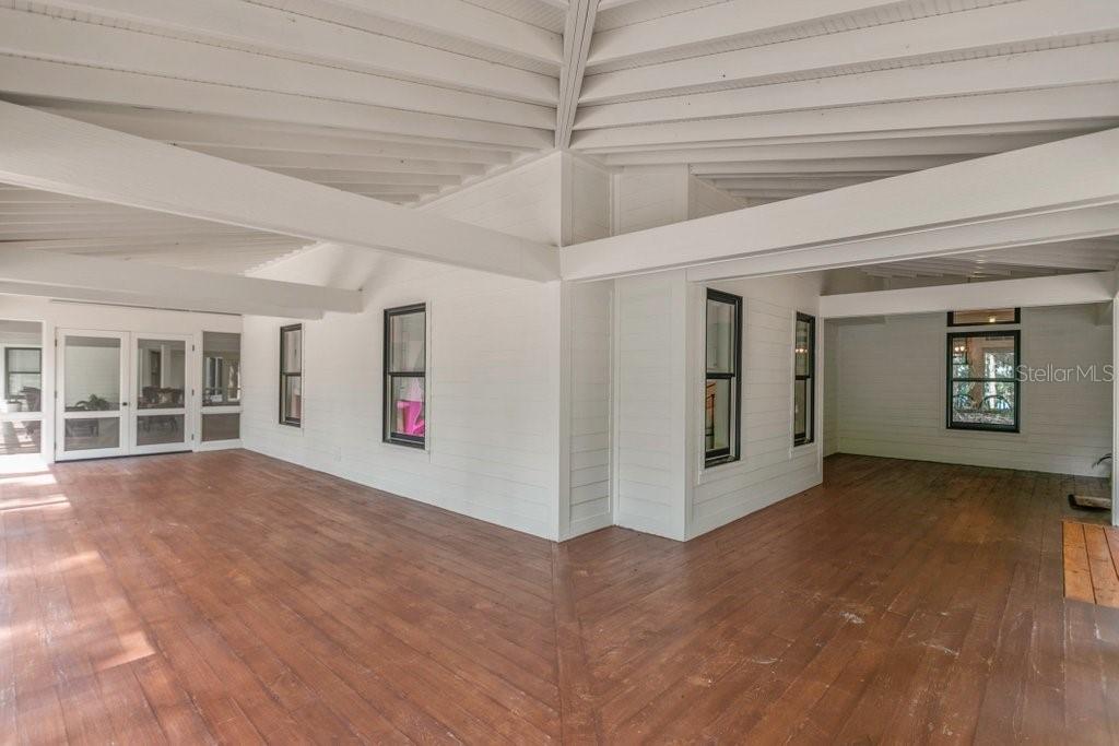 A covered outdoor porch with white walls, dark window frames, and a wooden floor — 645 S US HIGHWAY 17, SAN MATEO, FL
