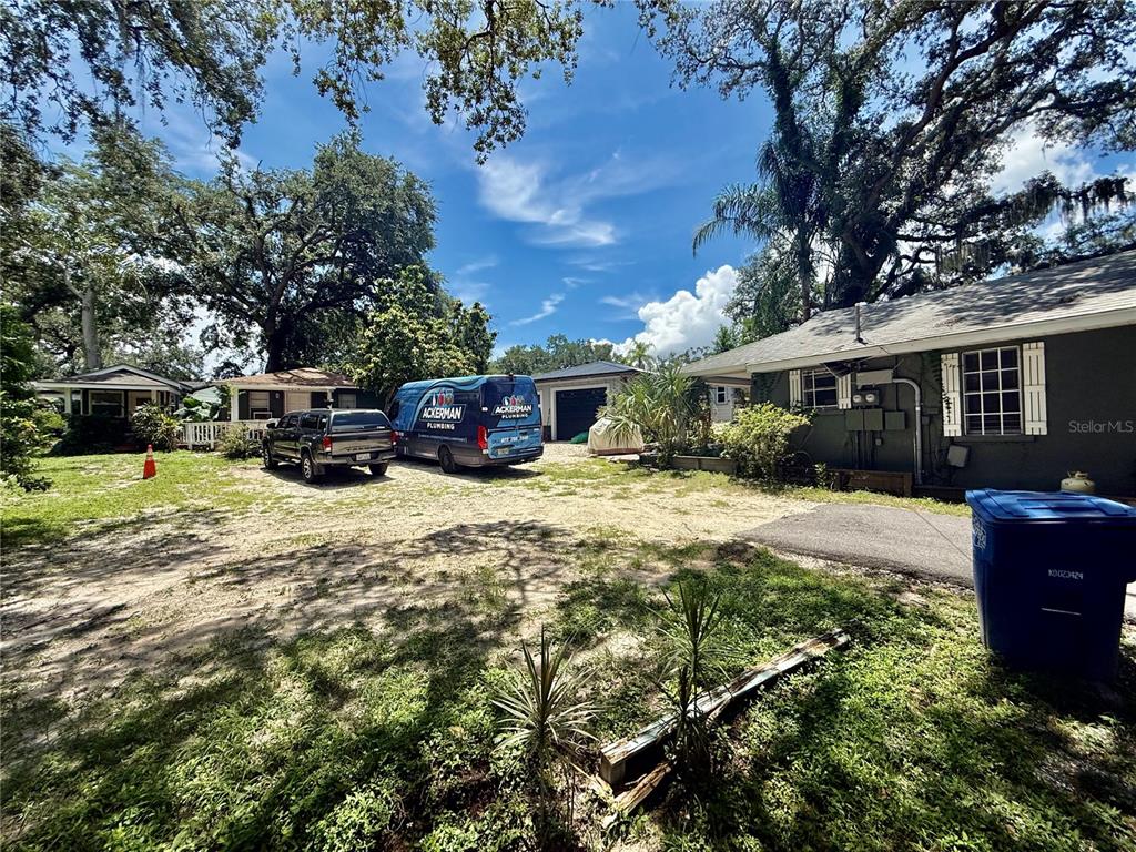 A gravel driveway leads to a house and detached garage with two plumbing service vehicles parked — 1014 W MOHAWK AVENUE, TAMPA, FL