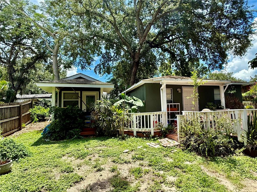 Two small, dark green detached buildings sit in a grassy yard under large oak trees — 1014 W MOHAWK AVENUE, TAMPA, FL