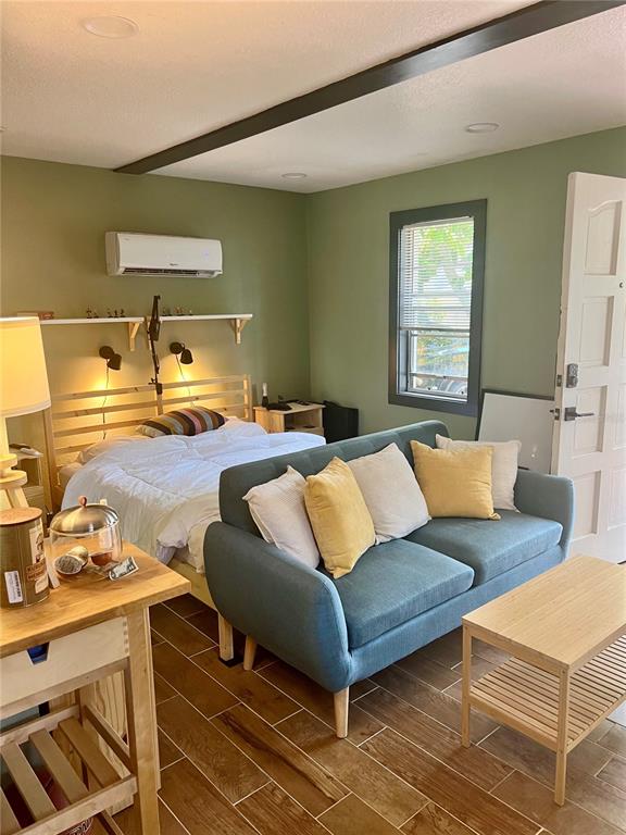 A studio apartment features a bed, a blue sofa, and wood-look tile flooring — 1014 W MOHAWK AVENUE, TAMPA, FL
