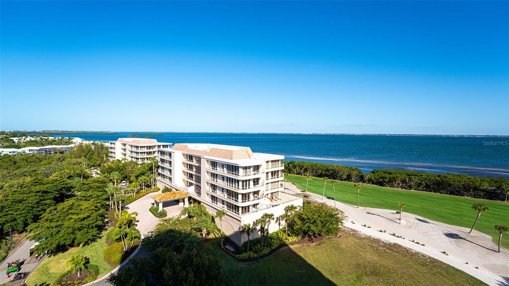 An aerial view shows a multi-story apartment building situated next to a golf course and ocean — 3060 GRAND BAY BOULEVARD UNIT 172, LONGBOAT KEY, FL