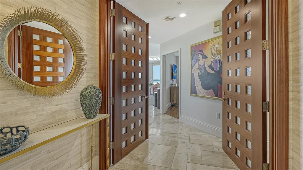 A foyer features a textured wall, a round mirror, and double doors leading to a hallway — 3060 GRAND BAY BOULEVARD UNIT 172, LONGBOAT KEY, FL