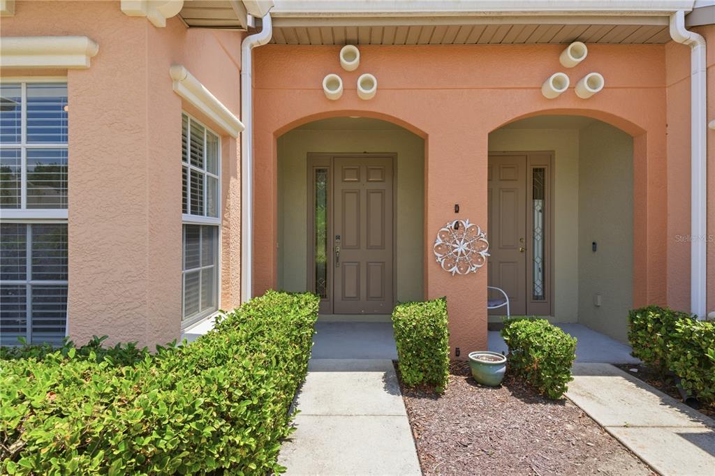 The exterior of a peach-colored building features two arched entryways with brown doors — 4620 1ST AVENUE E UNIT 4620, PALMETTO, FL