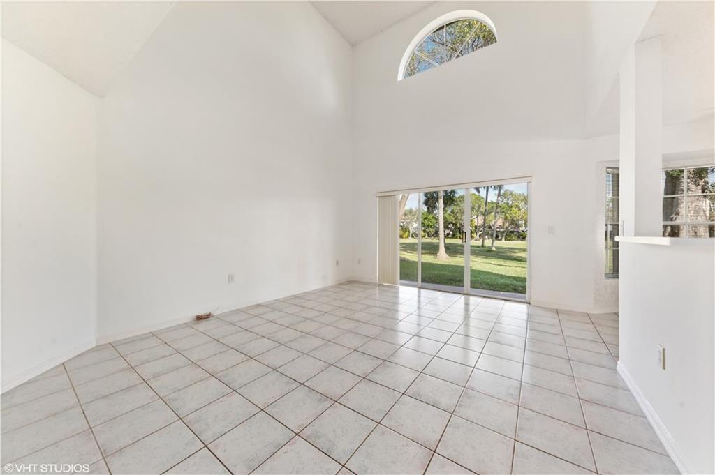 An empty room features white walls, tile flooring, a vaulted ceiling, and a sliding glass door — 7697 NW 25th Street, Margate FL 33063, MARGATE, FL