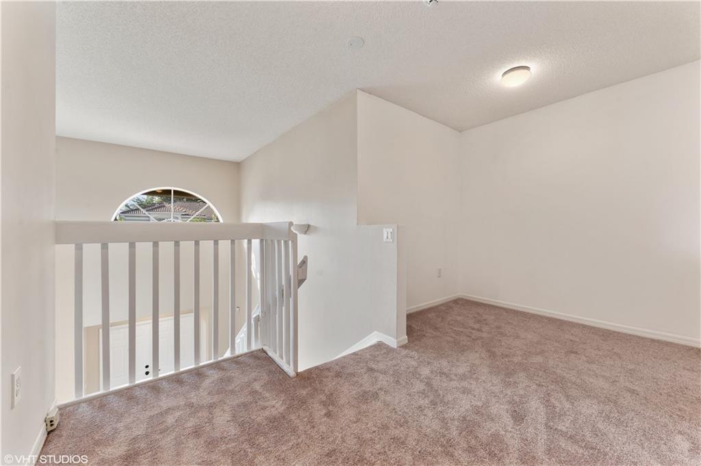 A carpeted loft area features a white railing overlooking a lower level and a window — 7697 NW 25th Street, Margate FL 33063, MARGATE, FL