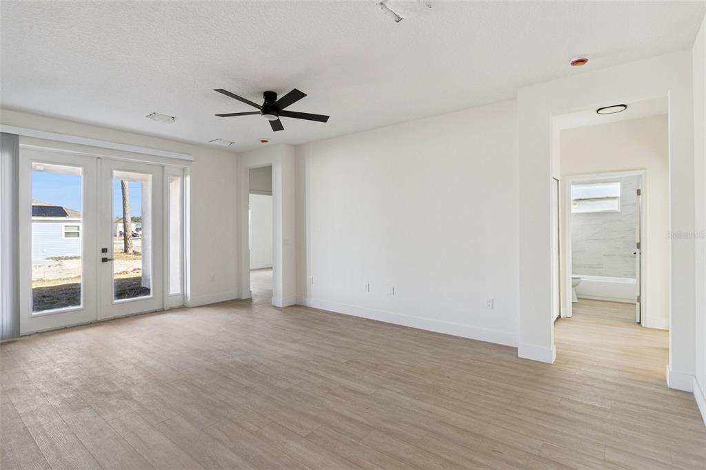 A bright living room with light wood-look flooring, a ceiling fan, and glass patio doors — 1201 APOPKA LANE, KISSIMMEE, FL