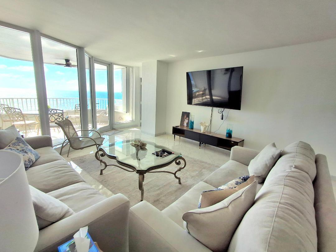 A living room features two sofas, a glass coffee table, and a wall-mounted television — 1340 S Ocean Boulevard # 1808, Pompano Beach FL 33062, POMPANO BEACH, FL