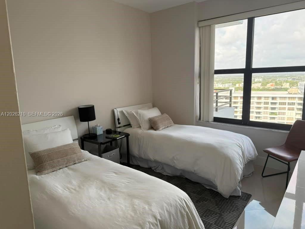A bedroom features two twin beds, a nightstand, and a large window with city views — 2500 Parkview Dr # 2518, Hallandale Beach FL 33009, HALLANDALE BEACH, FL