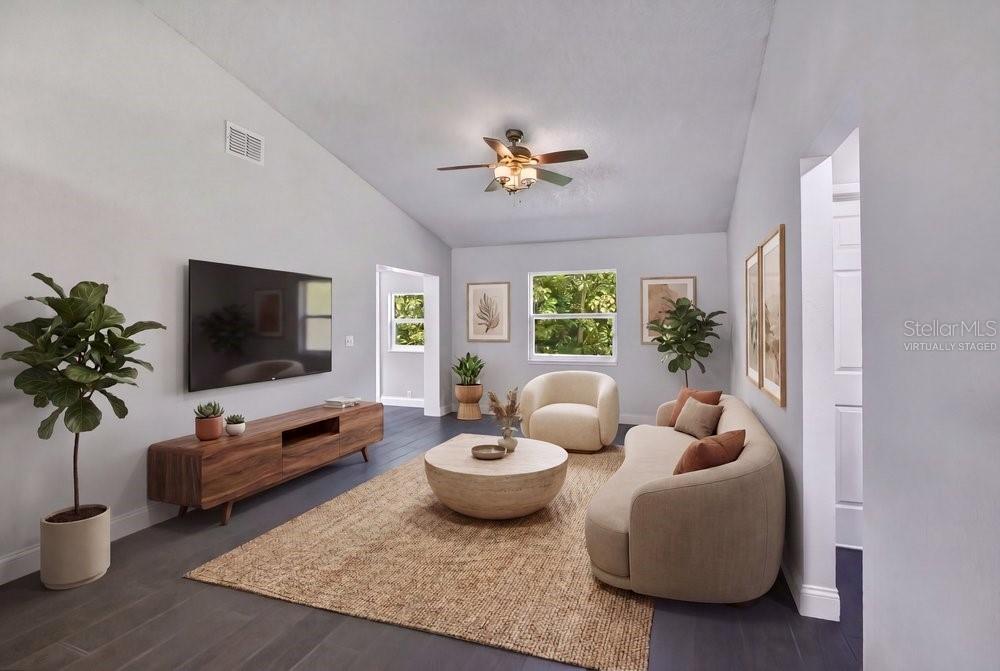 This virtually staged living room features dark wood-look flooring, a curved sofa, and a television — 156 LAKE DRIVE, ORLANDO, FL