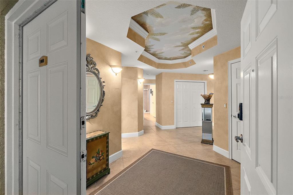 A foyer with tile floors, a painted tray ceiling, and a decorative console table — 2403 S ATLANTIC AVENUE UNIT 1008, DAYTONA BEACH SHORES, FL