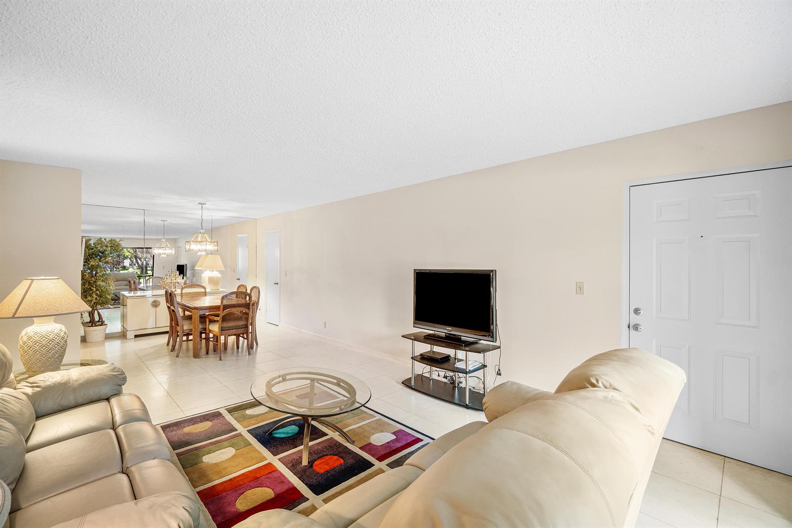 A living room with a colorful area rug, leather sofas, and an adjacent dining area — 9810 Pineapple Tree Drive # 101, Boynton Beach FL 33436, BOYNTON BEACH, FL