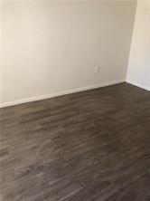 An empty room with light-colored walls and dark wood-look laminate flooring — 1001 Crystal Way, Delray Beach FL 33444, DELRAY BEACH, FL