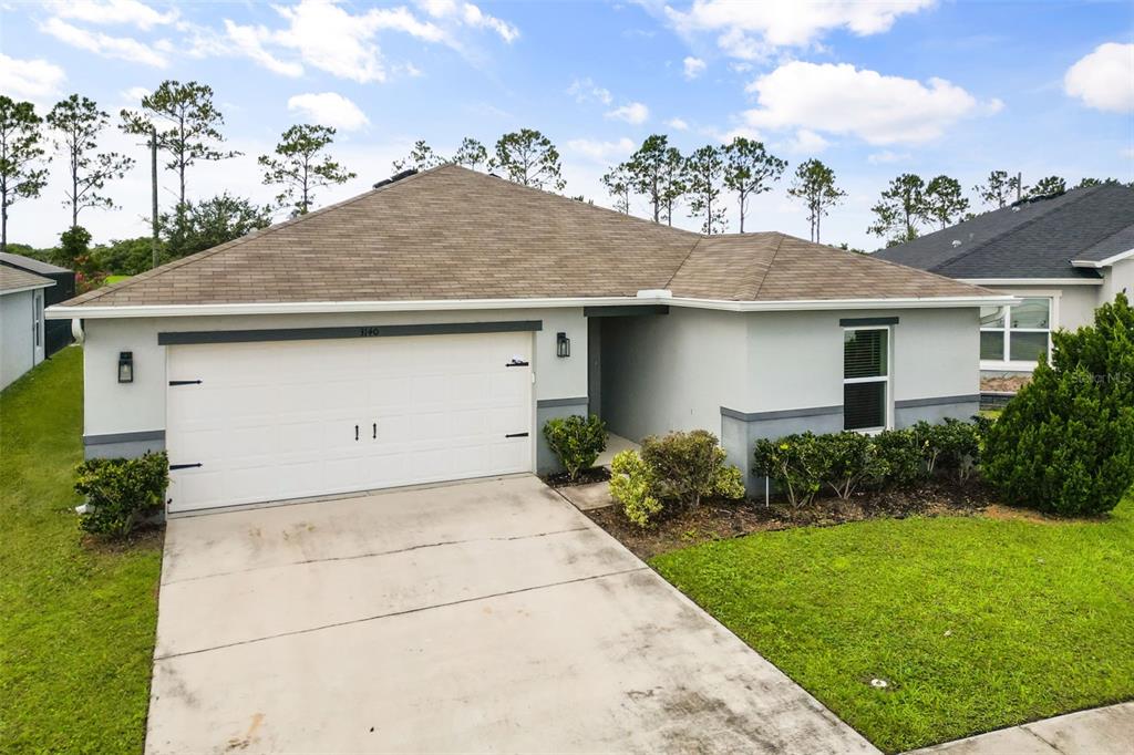 A single-story house with a white garage door, gray exterior walls, and a shingled roof — 3140 SWEET ACRES PLACE, ST CLOUD, FL