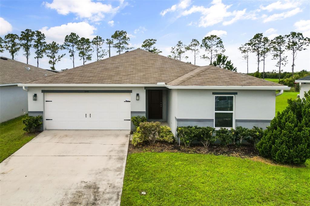 A single-story house with a white garage, gray trim, and a brown shingled roof — 3140 SWEET ACRES PLACE, ST CLOUD, FL
