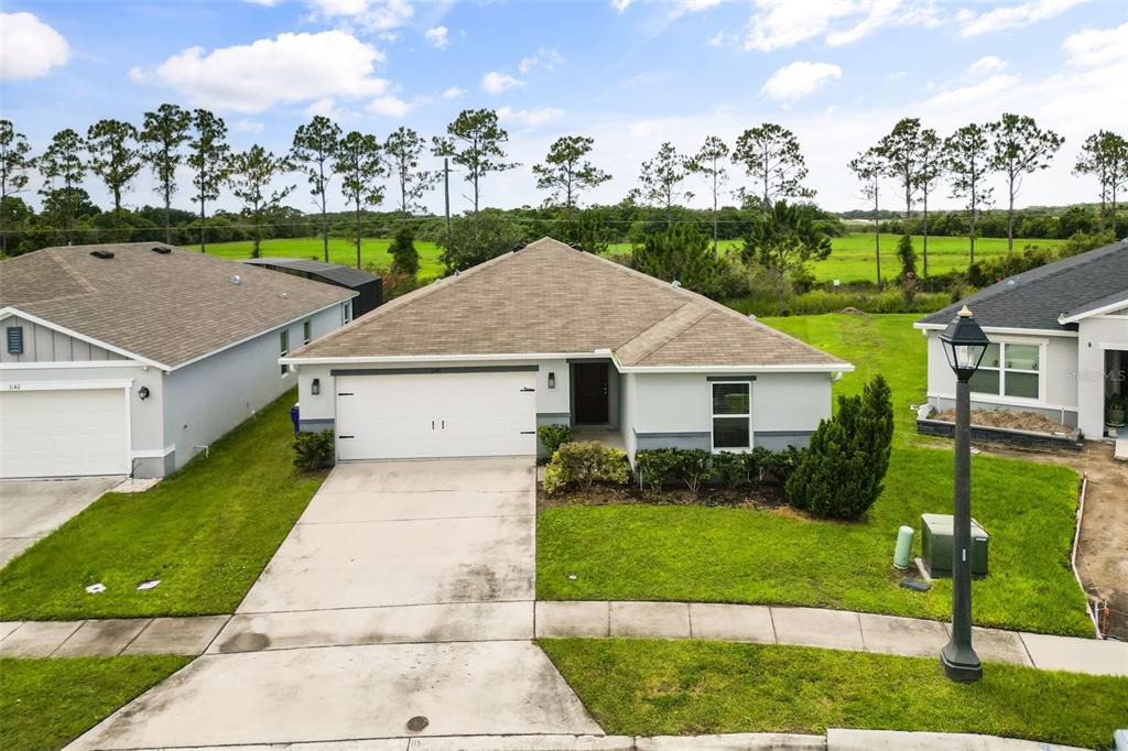 An exterior view of a single-story suburban house with a two-car garage and lawn — 3140 SWEET ACRES PLACE, ST CLOUD, FL