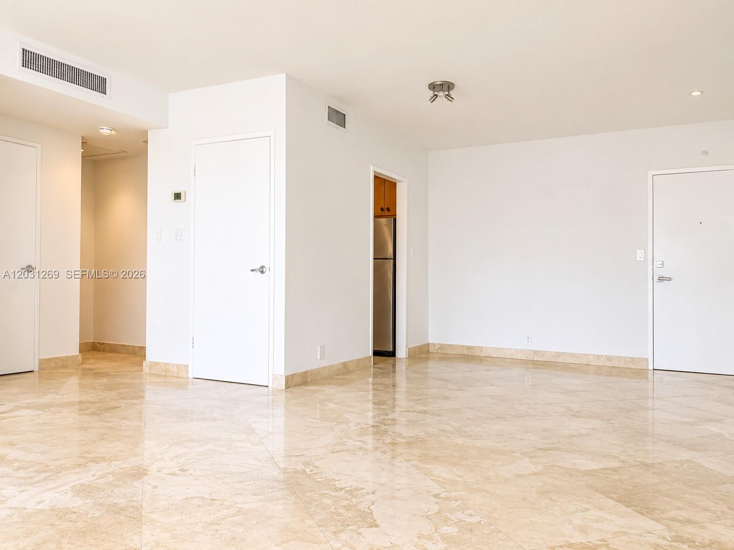 An empty room features white walls, beige marble flooring, and several white interior doors — 3301 NE 5th Ave # 908, Miami FL 33137, MIAMI, FL