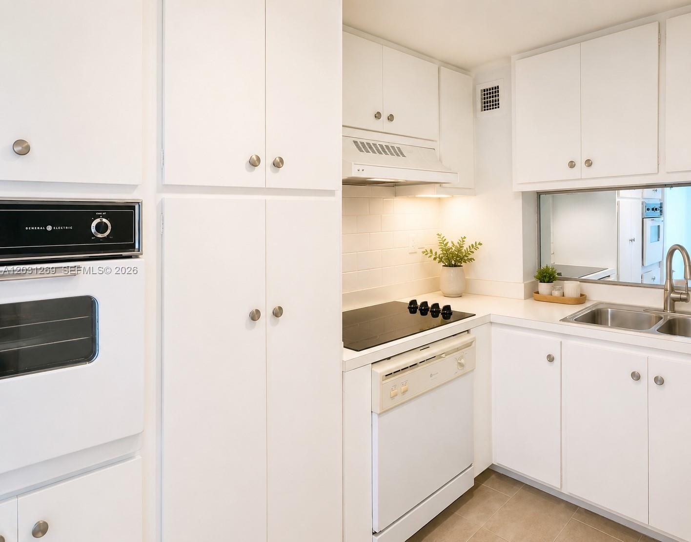 A white kitchen features a built-in oven, electric cooktop, and a pass-through window — 3301 NE 5th Ave # 908, Miami FL 33137, MIAMI, FL
