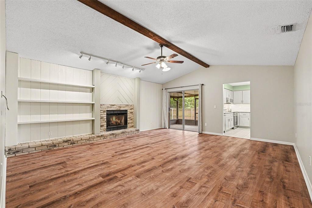 A living room features wood-look flooring, a brick fireplace, built-in shelves, and a ceiling fan — 17703 CRANBROOK DRIVE, LUTZ, FL