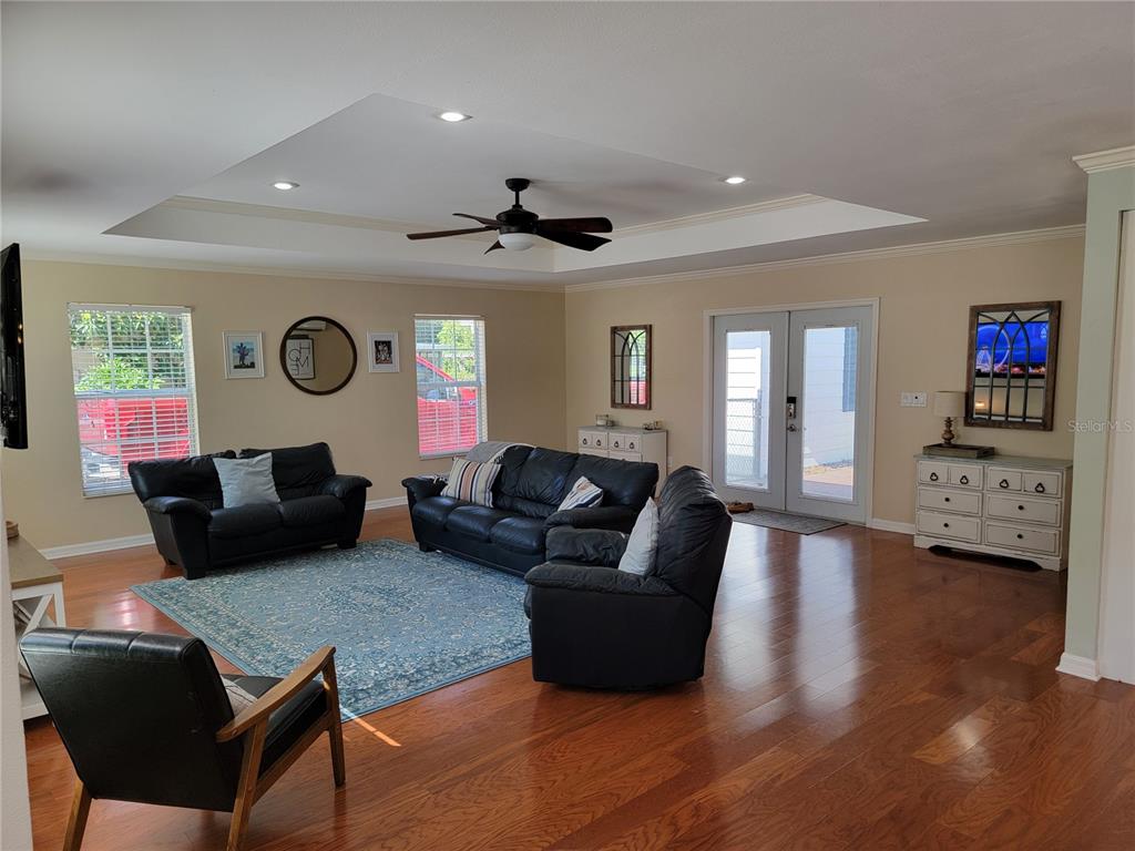 A living room features dark leather furniture, a blue area rug, and hardwood flooring — 4435 MOUNT VIEW DR, LAKELAND, FL
