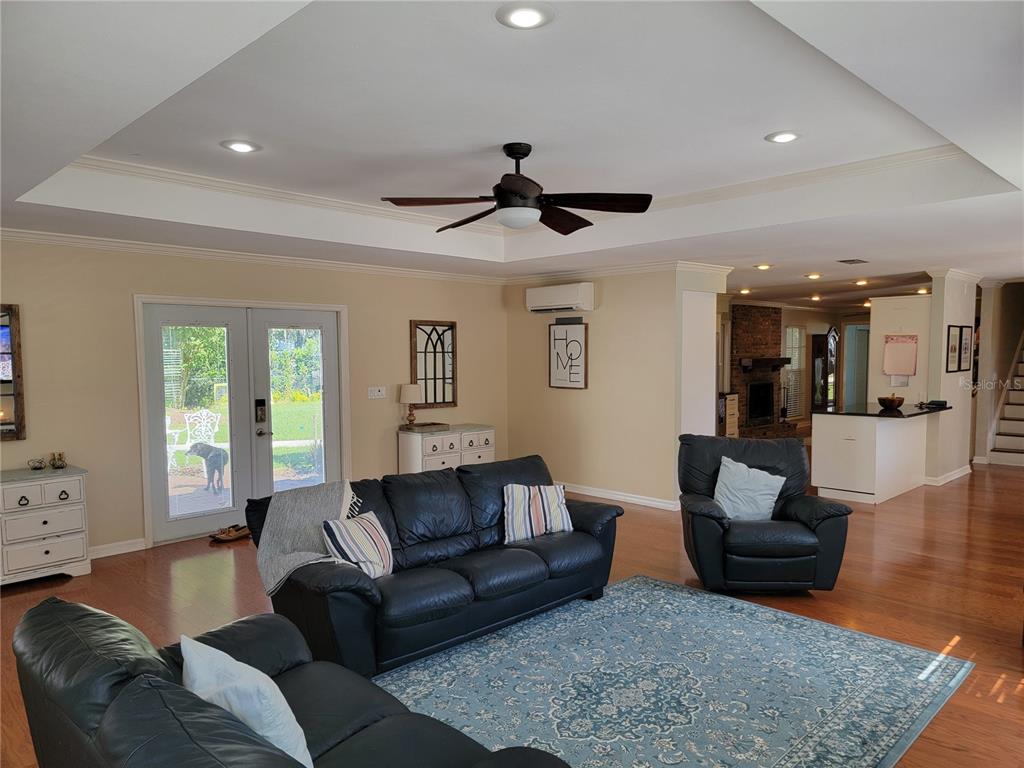 A living room with a tray ceiling, ceiling fan, black leather furniture, and hardwood floors — 4435 MOUNT VIEW DR, LAKELAND, FL