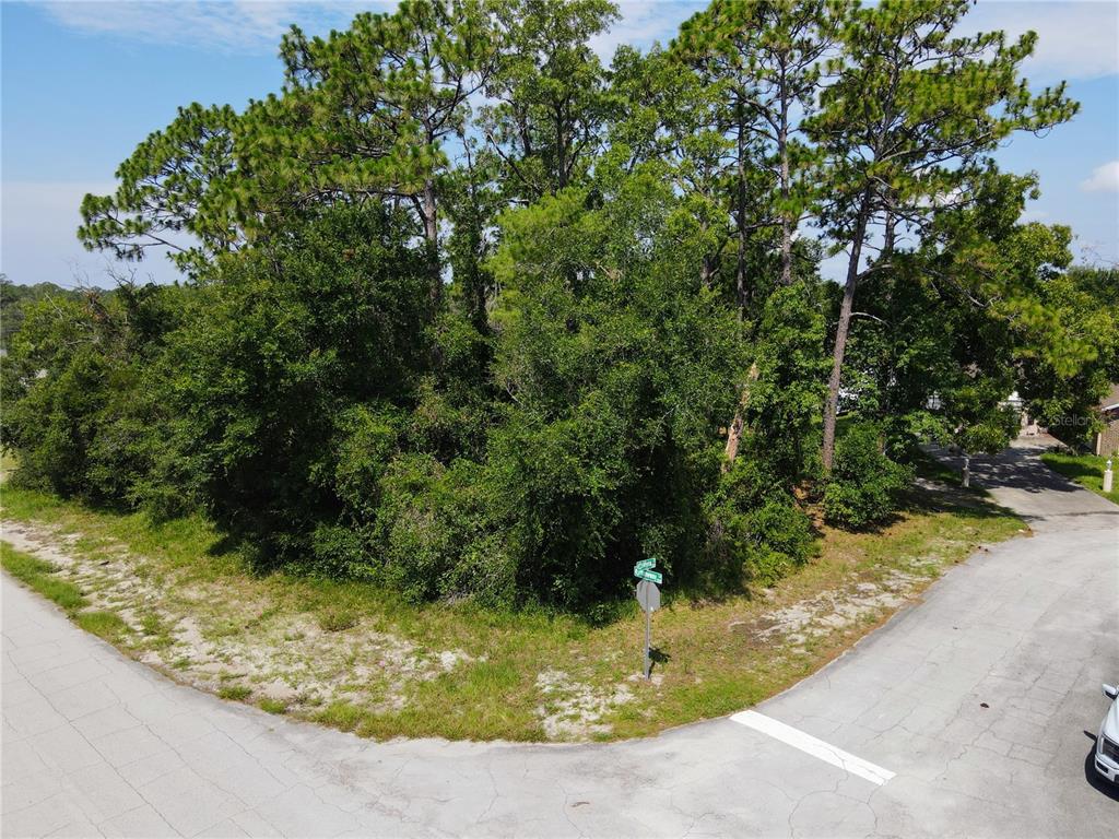 An aerial view shows a vacant, wooded corner lot at a residential street intersection — 1255 MYRA COURT, DELTONA, FL