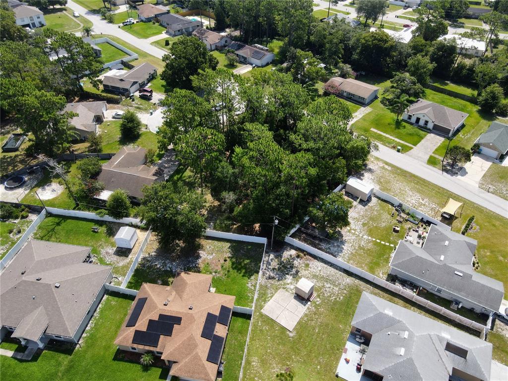 An aerial view shows several suburban houses with fenced yards and a central wooded area — 1255 MYRA COURT, DELTONA, FL