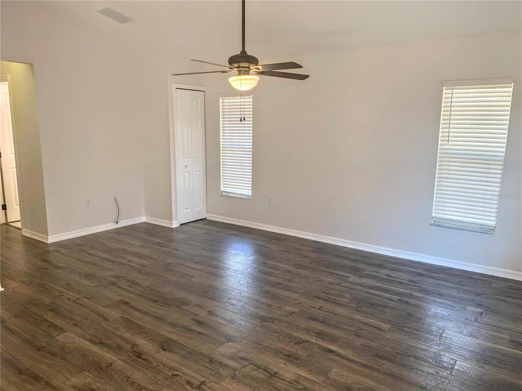 An empty room with wood-look flooring, a ceiling fan, and two windows with blinds — 5440 KENSINGTON STREET, SARASOTA, FL