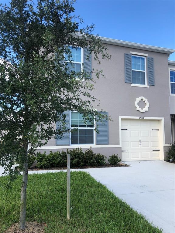 A green front door with a small sign is set into a beige stucco wall — 9035 CARLOTTA WAY, KISSIMMEE, FL