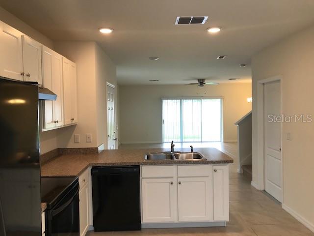 An open-concept living area features tile flooring, a ceiling fan, and a staircase — 9035 CARLOTTA WAY, KISSIMMEE, FL