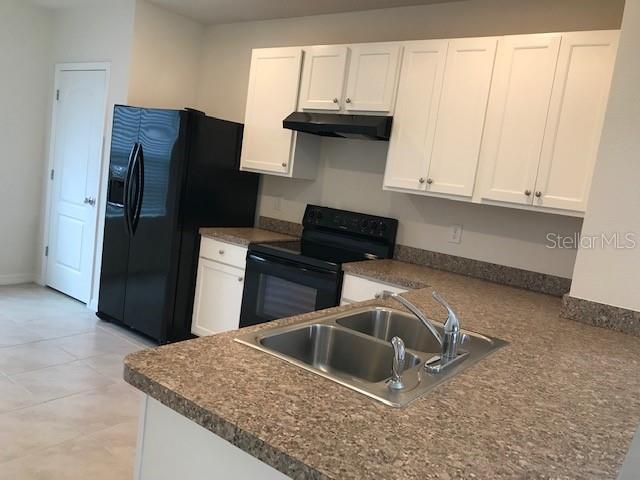 An open-concept living area features tile flooring, a ceiling fan, and a staircase — 9035 CARLOTTA WAY, KISSIMMEE, FL