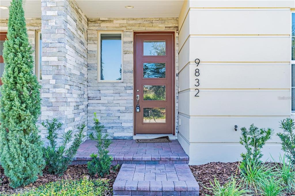 A front entrance features a brown door with four glass panels and stone veneer siding — 9832 BUCKLOW HILL DRIVE, ORLANDO, FL