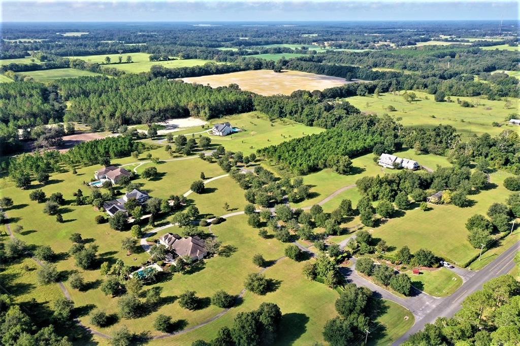 An aerial view shows several houses situated on a large, grassy, tree-filled rural lot — 1680 SW 188TH STREET, NEWBERRY, FL