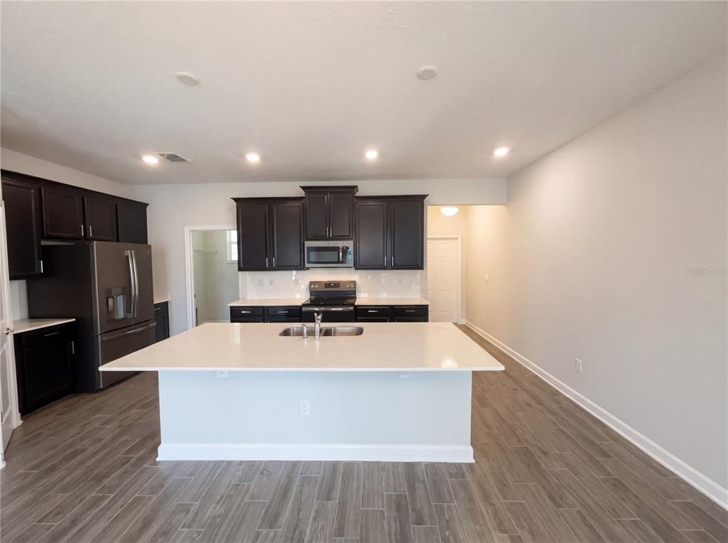 A kitchen with dark cabinets, a large white island, and wood-look tile flooring — 11072 SILVER SURFER ALLEY, WINTER GARDEN, FL