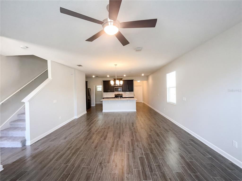 An open-concept living area features wood-look tile flooring, a ceiling fan, and a kitchen island — 11072 SILVER SURFER ALLEY, WINTER GARDEN, FL