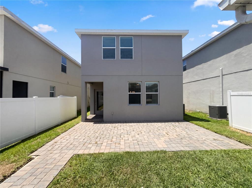 The exterior rear view of a two-story house features a paved patio and white fencing — 11072 SILVER SURFER ALLEY, WINTER GARDEN, FL
