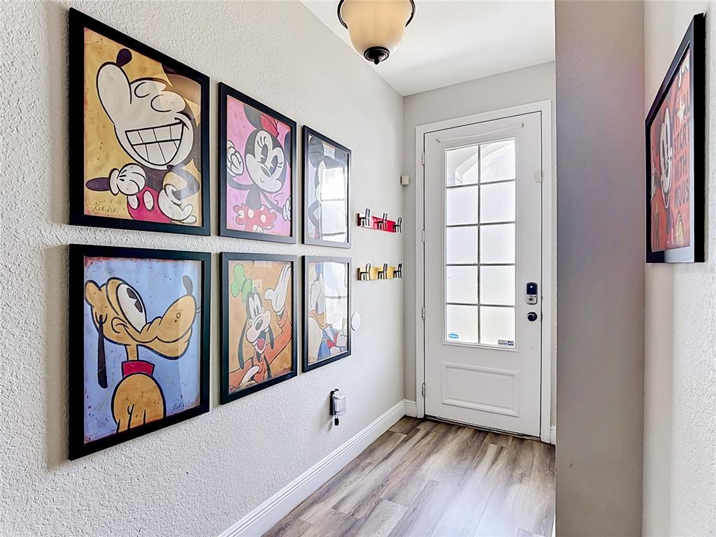 A hallway features six framed Disney character prints on the wall and a white door — 7674 OTTERSPOOL STREET, KISSIMMEE, FL