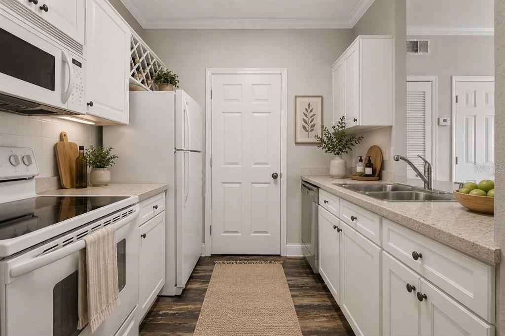A galley kitchen features white cabinets, stainless steel appliances, and a light-colored countertop — 1216 S MISSOURI AVENUE UNIT 116, CLEARWATER, FL
