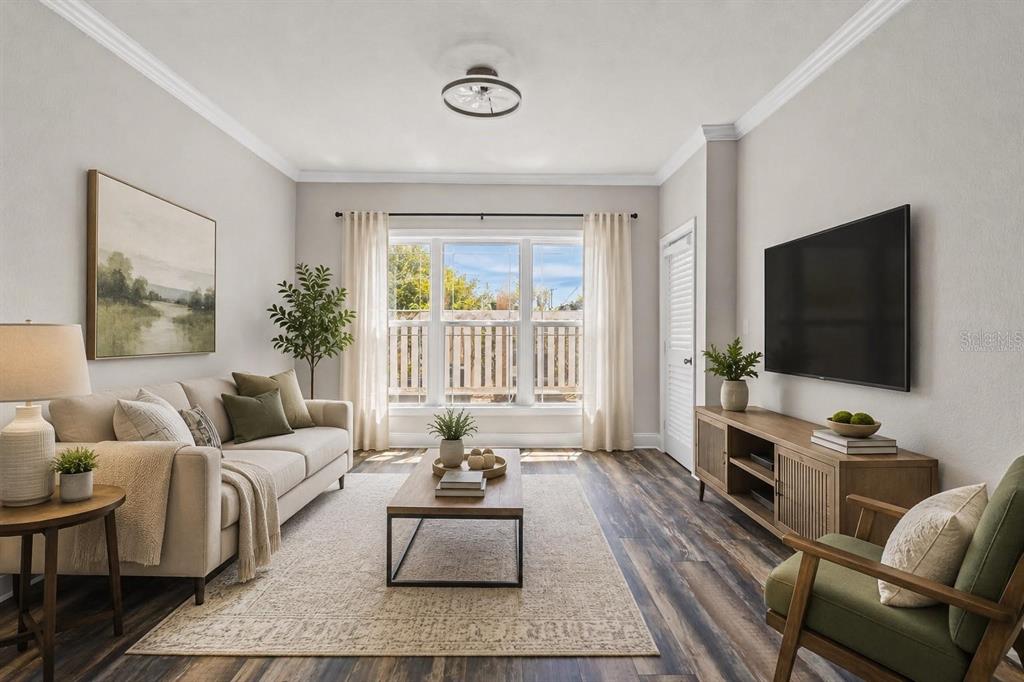 A living room features a beige sofa, wood coffee table, media console, and large window — 1216 S MISSOURI AVENUE UNIT 116, CLEARWATER, FL