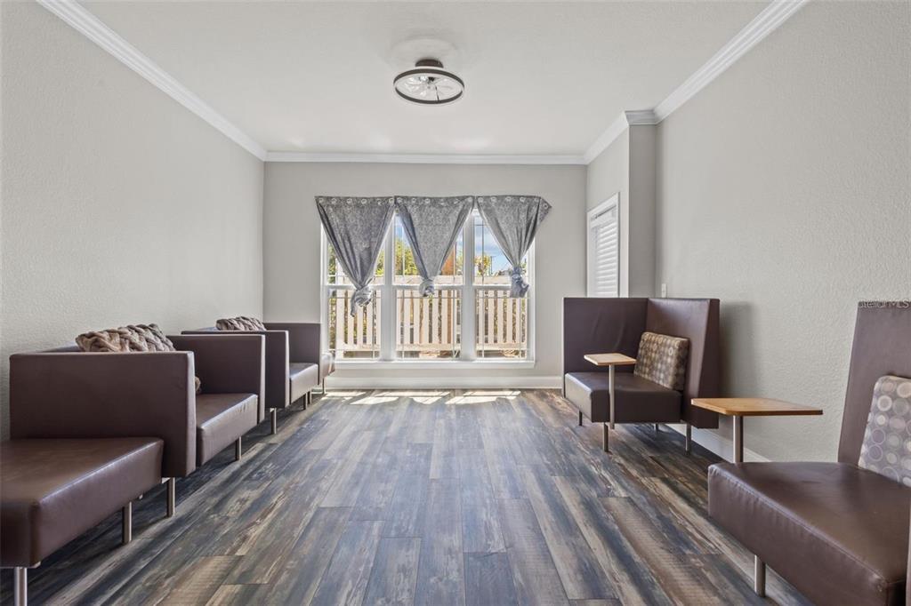 A waiting room features brown leather chairs, wood-look flooring, and a large window with curtains — 1216 S MISSOURI AVENUE UNIT 116, CLEARWATER, FL