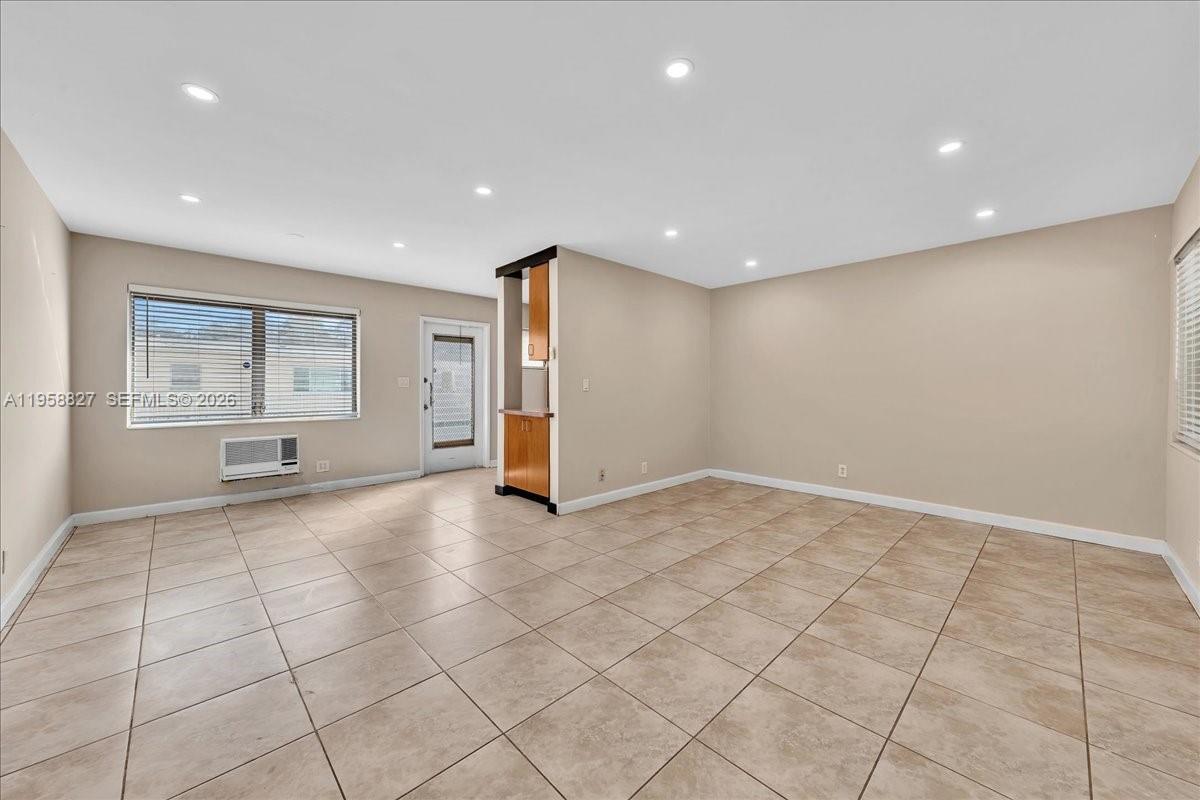 An empty room features beige walls, light-colored tile flooring, recessed lighting, and a window unit — 707 S 19th Ave # 9, Hollywood FL 33020, HOLLYWOOD, FL