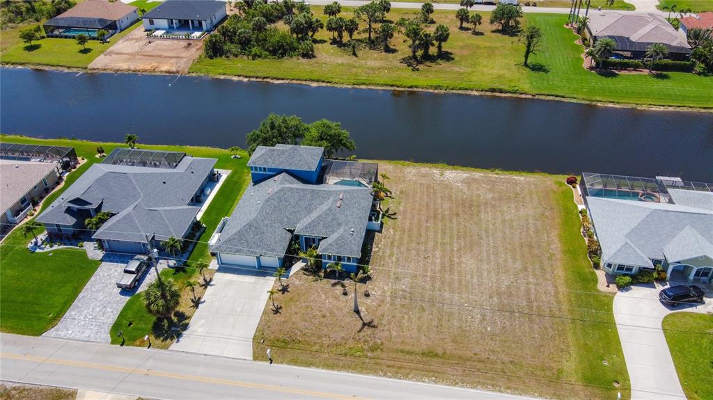 An aerial view shows a blue house with a pool next to a vacant lot — 1167 ROTONDA CIRCLE, ROTONDA WEST, FL