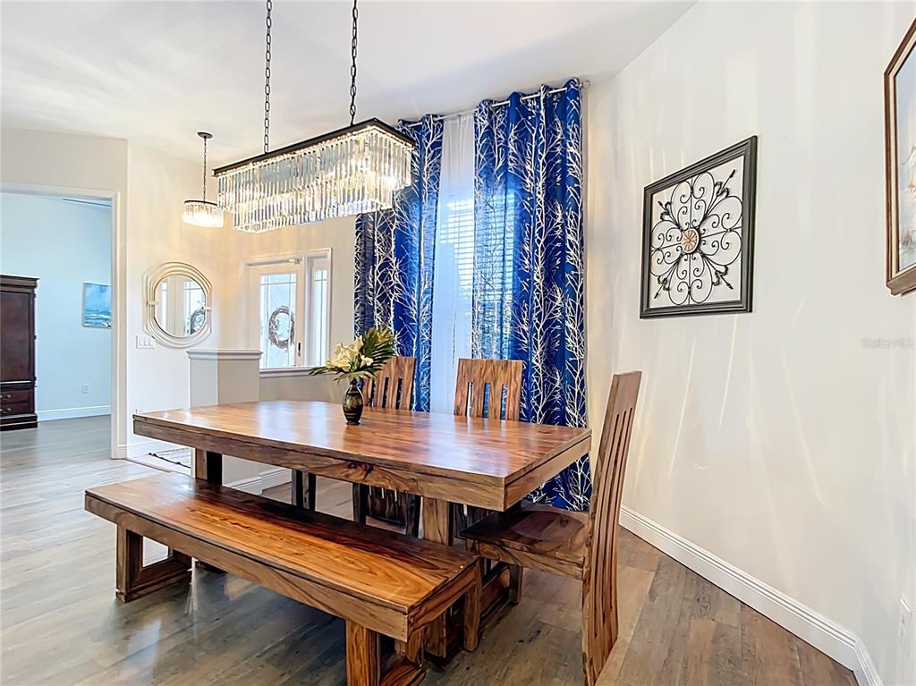 A dining room features a wooden table with a bench, chairs, and a crystal chandelier — 1167 ROTONDA CIRCLE, ROTONDA WEST, FL