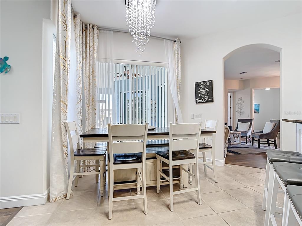 A dining area features a wooden table with white chairs, a crystal chandelier, and curtains — 1167 ROTONDA CIRCLE, ROTONDA WEST, FL
