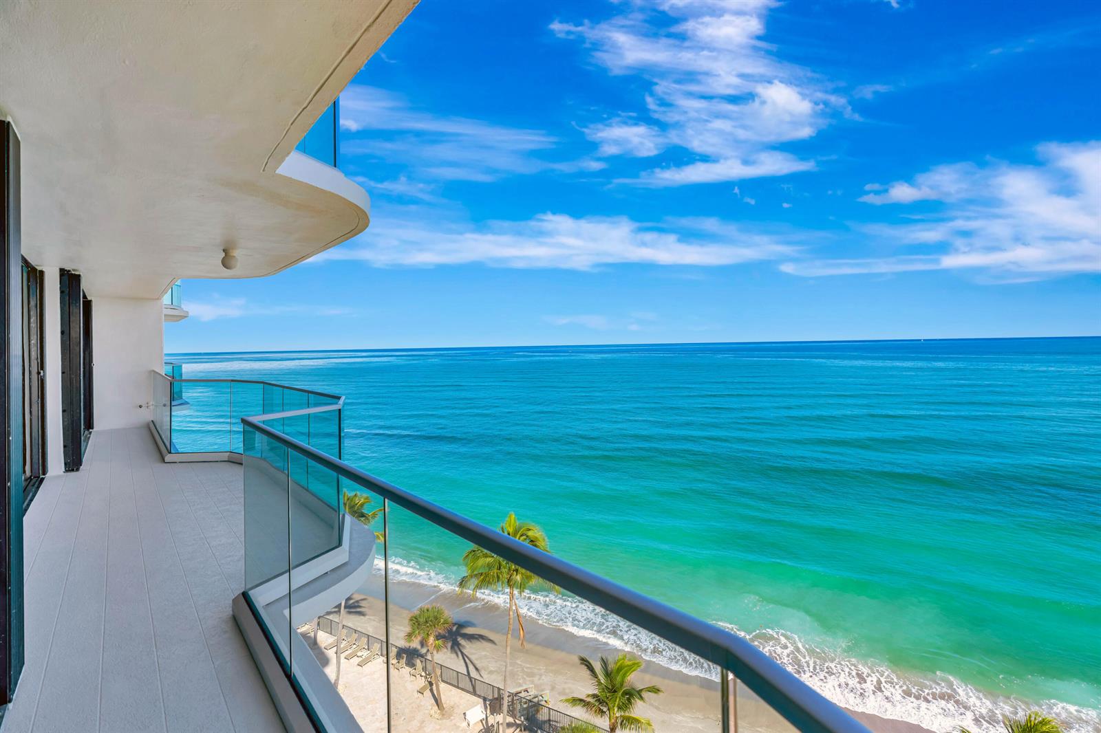 A high-rise balcony with a glass railing overlooks a sandy beach and the turquoise ocean — 100 S Beach Road, Jupiter FL 33469, JUPITER, FL