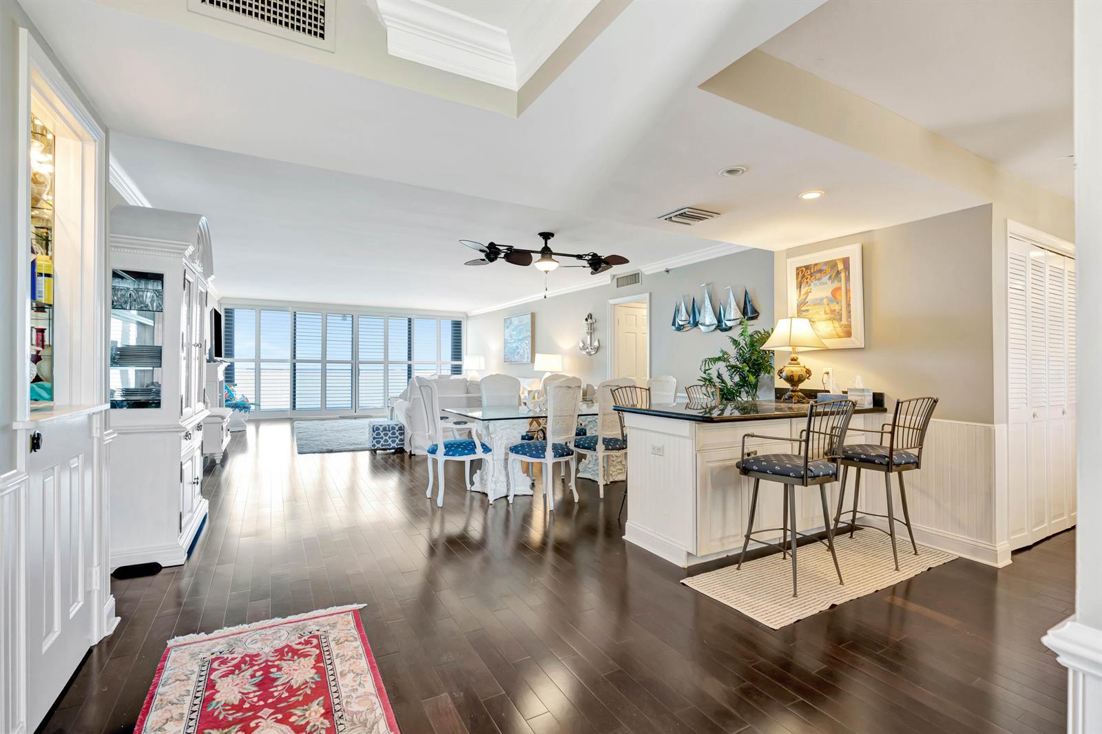 A bright, open-concept living and dining area features dark hardwood floors and a kitchen island — 100 S Beach Road, Jupiter FL 33469, JUPITER, FL