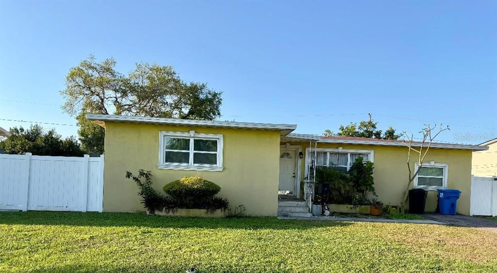 A single-story yellow house features a white front door, two windows, and a white fence — 3624 ABINGTON AVENUE S, ST PETERSBURG, FL