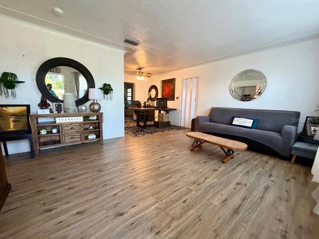 A living room features wood-look flooring, a gray sofa, and a wooden console table — 3624 ABINGTON AVENUE S, ST PETERSBURG, FL