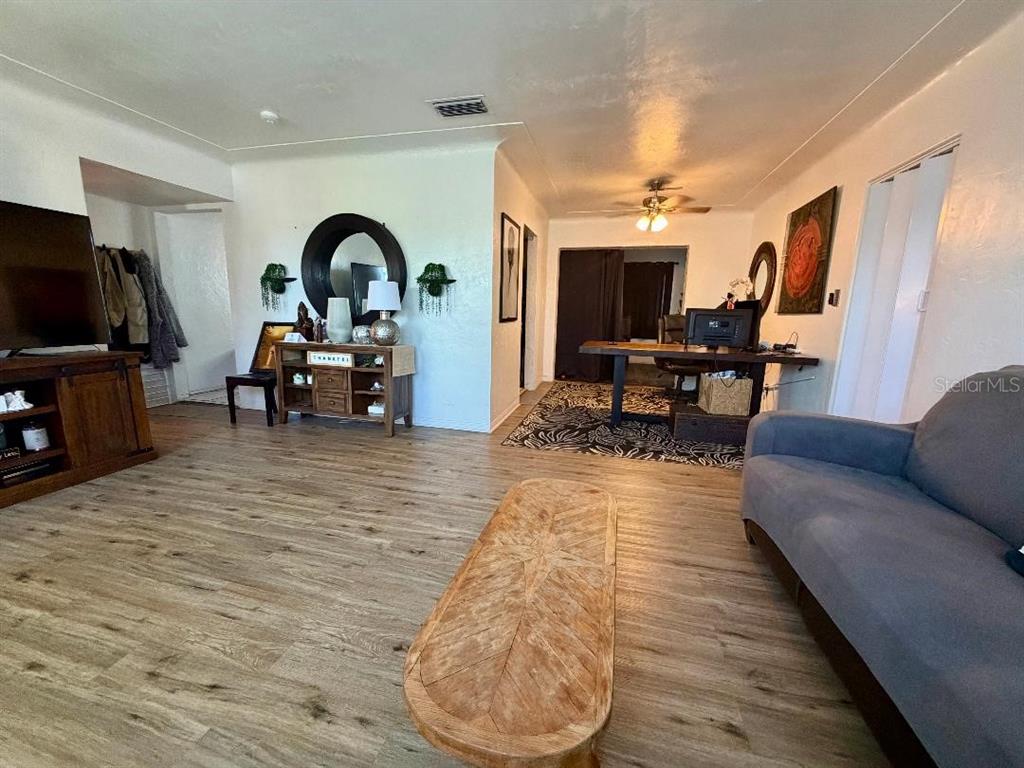 A living room with wood-look flooring, a gray sofa, and a wooden desk area — 3624 ABINGTON AVENUE S, ST PETERSBURG, FL
