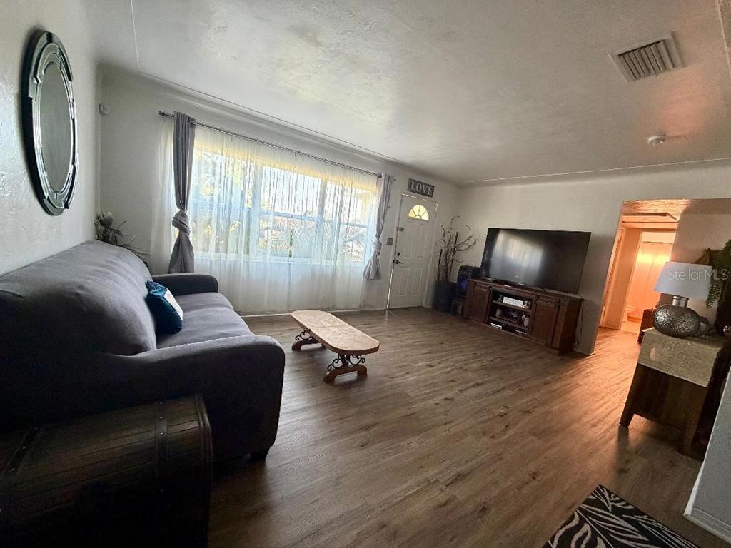 A living room features wood-look flooring, a gray sofa, a coffee table, and a television console — 3624 ABINGTON AVENUE S, ST PETERSBURG, FL